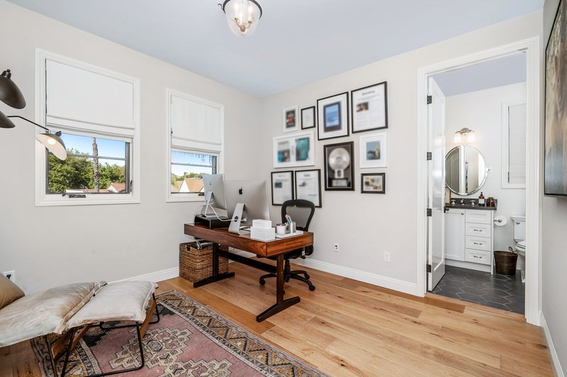 Un escritorio pequeño está colocado junto a una silla y una lámpara en el suelo.